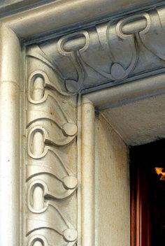 an ornate design on the side of a building's door, with a clock in the foreground