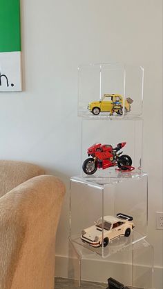 three cars are stacked on top of each other in a clear acrylic display case