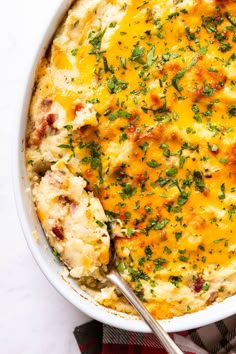 a casserole with cheese and herbs in a white dish on a checkered table cloth