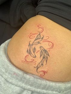 a woman's stomach with a tattoo on the side of her belly and two goldfish