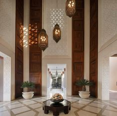 an elegant lobby with chandeliers and potted plants on the table in front of it