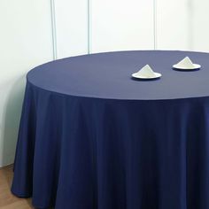 two white plates sit on top of a blue table cloth that is draped over it