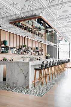 an instagramted photo of a bar with marble counter tops and chairs in front of it