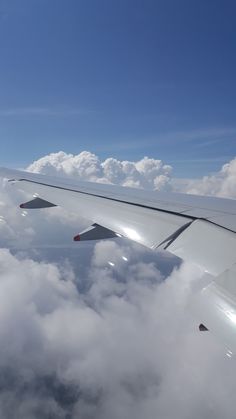 the wing of an airplane flying above some clouds