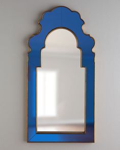 a blue mirror hanging on the wall next to a white wall with a light shining through it