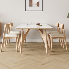 a dining room table with four chairs and a potted plant