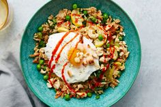 a blue plate topped with rice, peas and an egg