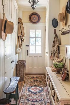 the hallway is clean and organized with hats hanging on the wall, an entryway rug, and a bench