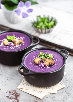 two black pans filled with purple sweet potato and mushroom soup on top of a table