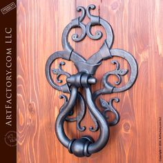 an ornate iron door handle on a wooden door