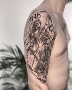 a man's arm with a clock and lady justice tattoo on the left shoulder