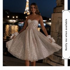 a woman in a short white dress standing next to the eiffel tower at night