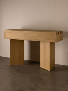 a large wooden bench sitting on top of a cement floor next to a white wall