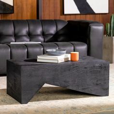 a coffee table sitting on top of a carpeted floor next to a black couch