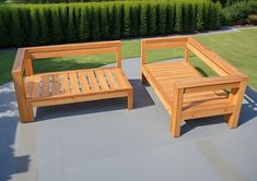 two wooden benches sitting next to each other on top of a cement floor in front of a lush green field