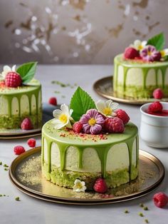 two cakes with green icing and raspberries on plates next to each other