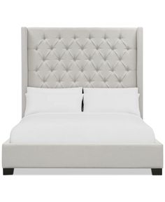 an upholstered bed with white linens and black piping on the headboard