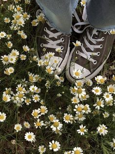 someone's feet standing in the grass surrounded by daisies