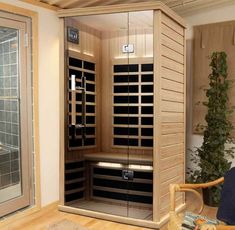 a person sitting in a wooden sauna with glass doors on the inside and outside