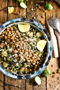 a bowl filled with lots of food on top of a wooden table next to a fork