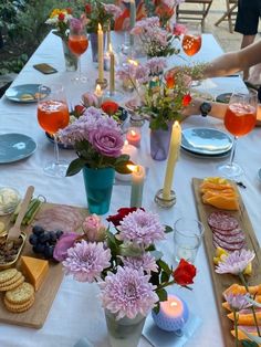 a long table is set with flowers, crackers and cheeses for a party