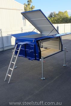 a blue portable toilet sitting on top of a parking lot next to a white building