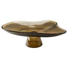 a brown and black plate sitting on top of a wooden tablecloth covered cake stand