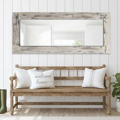 a wooden bench sitting under a large mirror