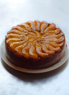 a round cake on a white plate with orange slices