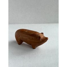 a small wooden pig figurine on a white surface