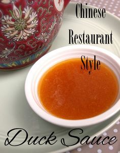 a bowl of soup sitting on top of a white plate next to a red teapot