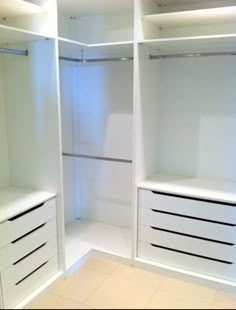 an empty walk in closet with all white drawers and shelves on each side, along with no doors