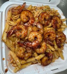 a plastic container filled with pasta covered in shrimp and sauce on top of it's side