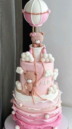 a pink and white cake with teddy bears on top