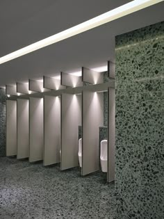 an empty public restroom with urinals and lights on the wall next to them