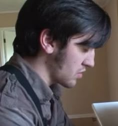 a man sitting in front of a laptop computer looking at the screen with an angry look on his face