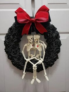 a wreath with a skeleton and a red bow hanging from it's front door