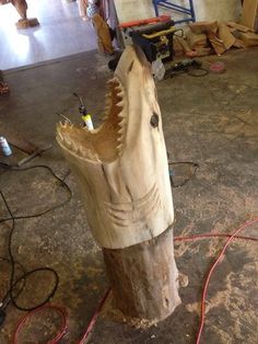 a wooden horse head on the ground in a building with wires and tools around it