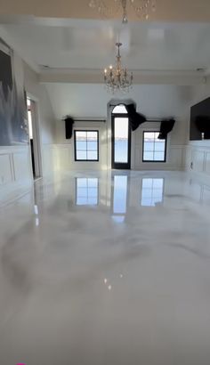 an empty room with chandelier, windows and white flooring is pictured in this image