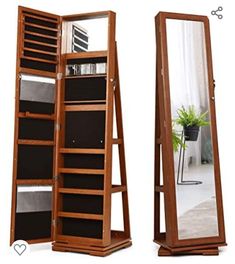 a tall wooden mirror with shelves and drawers in it's center, next to a plant on the floor