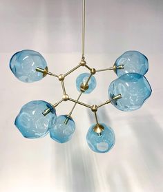 a blue glass chandelier hanging from a metal rod with five lights on each end