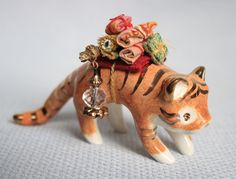 a ceramic tiger figurine with flowers on its back and bells hanging from it's neck