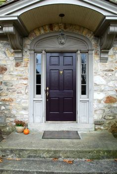 a purple front door with two pumpkins on the steps