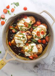 chicken with tomatoes and mozzarella sauce in a skillet on a marble surface