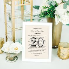 a table topped with white flowers next to a vase filled with greenery and candles