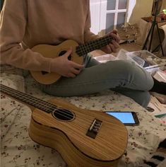 a person sitting on a bed playing an ukulele