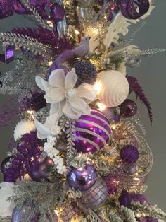 a purple and white christmas tree with ornaments on it's branches, lights and decorations