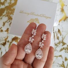 a person holding two pairs of earrings in their hand