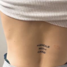 a woman's lower back with the words handle with care written on her left side