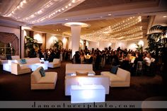 a room filled with lots of white couches and chairs next to tables covered in lights